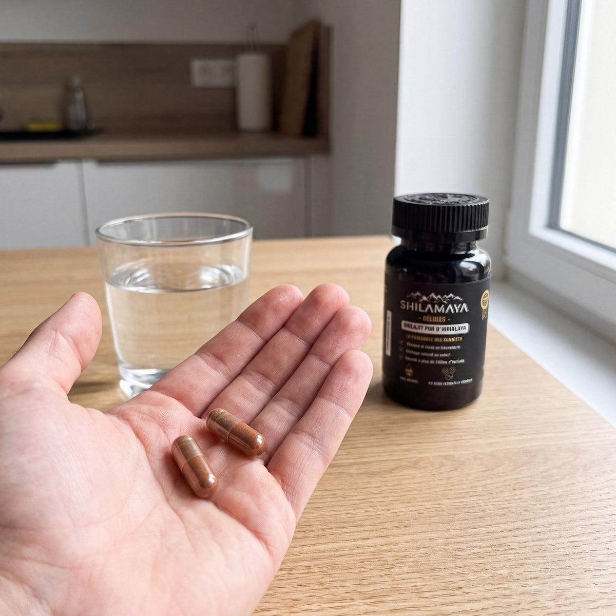 Deux gélules de Shilajit dans la main avec un verre d'eau