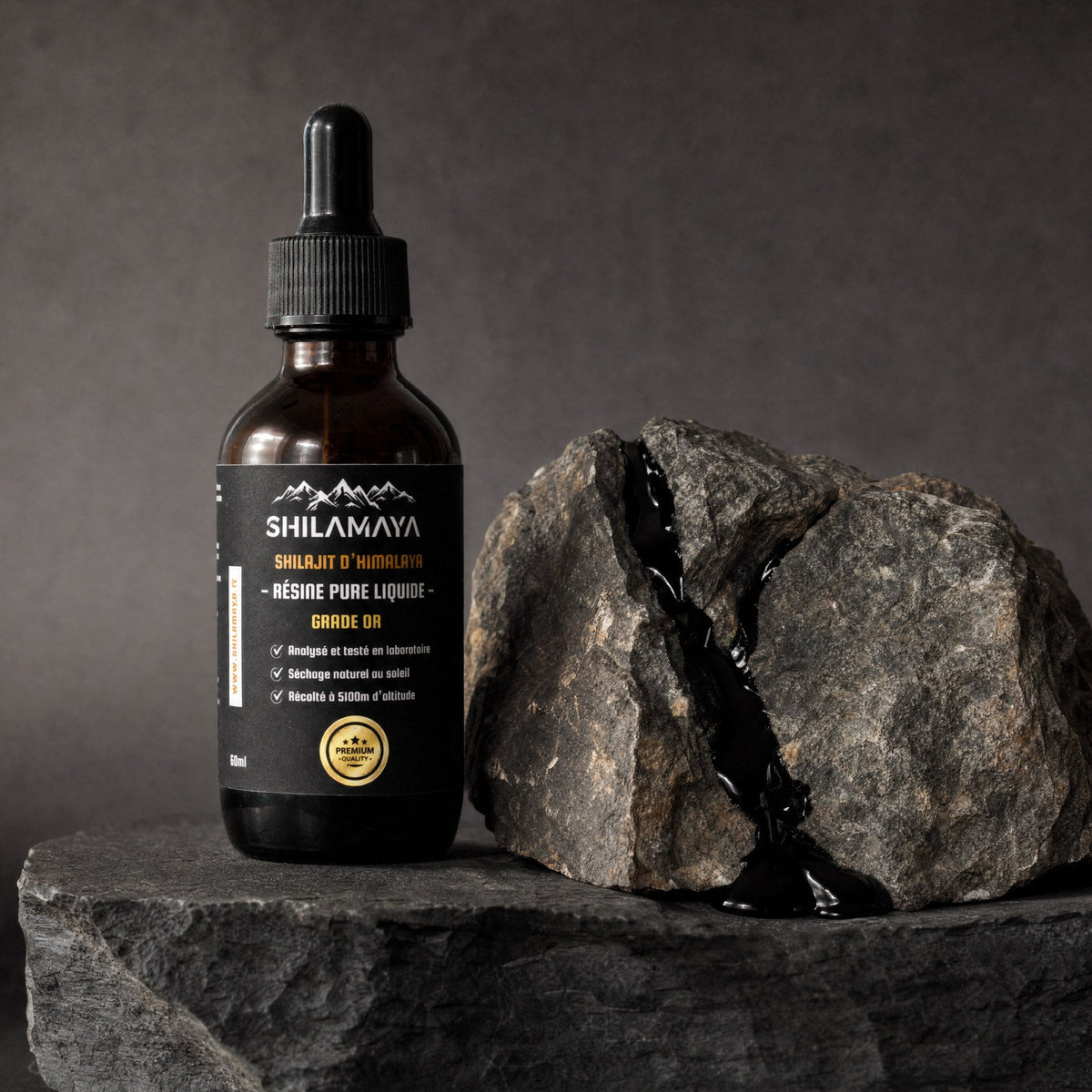 Flacon de Shilajit liquide posé sur la roche brute de l'Himalaya