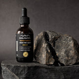 Flacon de Shilajit liquide posé sur la roche brute de l'Himalaya