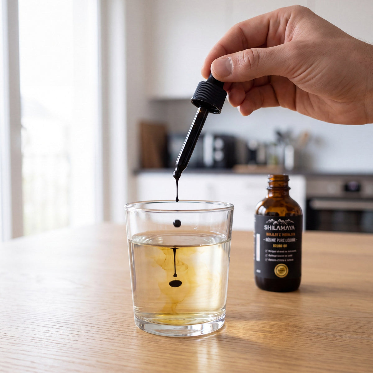Deux à trois gouttes de Shilajit liquide versées dans un verre d'eau